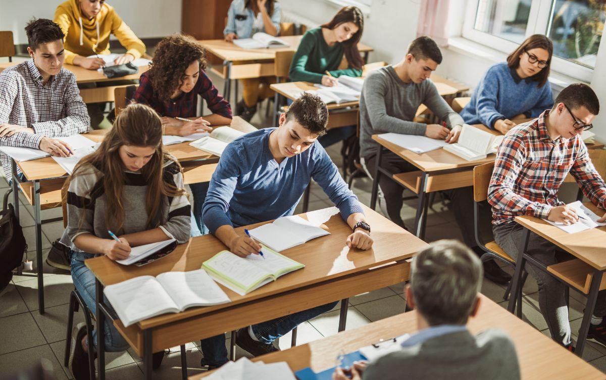 Studenti del liceo scientifico seduti ai banchi durante una lezione, intenti a scrivere e consultare libri Studenti del liceo scientifico seduti ai banchi durante una lezione, intenti a scrivere e consultare libri